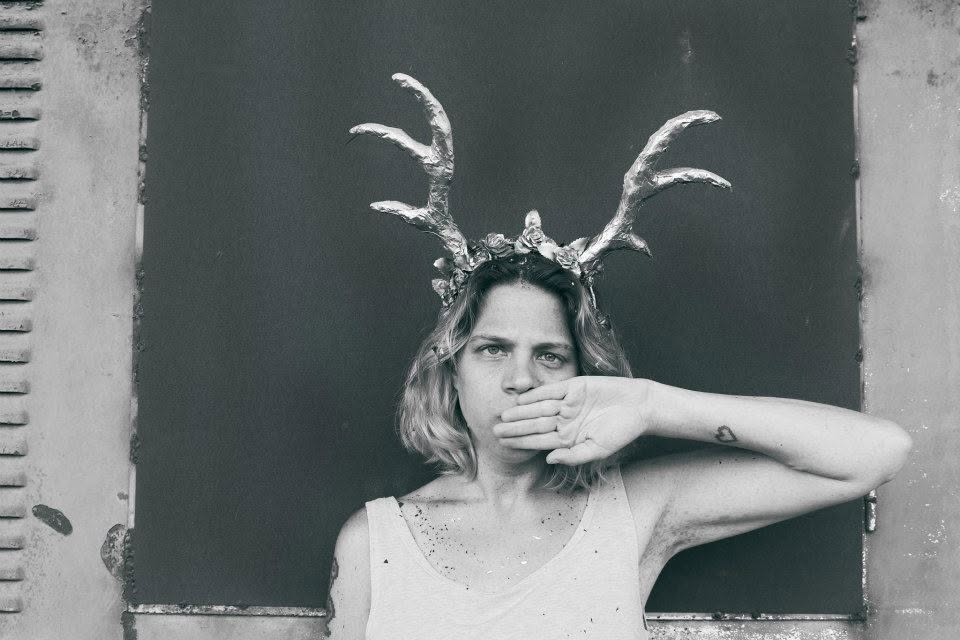 Hagara Ben Yishay, wearing antlers, a hand over her mouth.